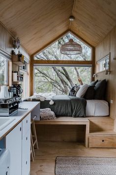 a bed sitting inside of a wooden room next to a sink and stove top oven