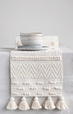 a white place setting with tassels and plates