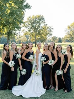 a group of women standing next to each other on top of a grass covered field