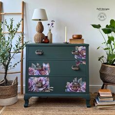 a green dresser with flowers painted on the drawers and plants in baskets next to it