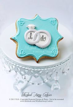 a cookie decorated with two wedding rings on top of a white cake platter that says i do