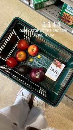 a person standing next to a shopping cart filled with apples and other fruit items on top of it