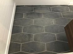 a bathroom floor with hexagonal tiles in grey and white colors on the walls