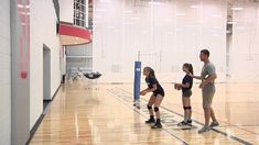 three people standing on a basketball court with one holding a ball and the other wearing knee pads