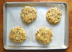 four cookies sitting on top of a baking pan covered in toppings, ready to be baked