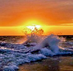 the sun is setting over the ocean with waves crashing in front of an orange and yellow sky