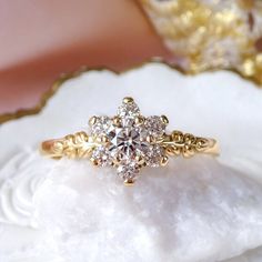 a diamond ring sitting on top of a piece of white rock next to a gold plate