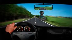 a person driving a car on a road with trees in the background