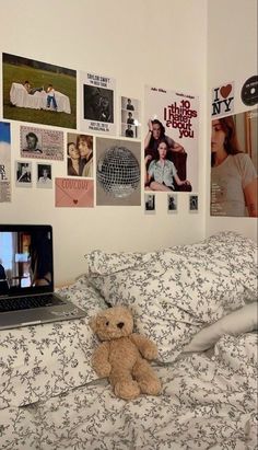 a laptop computer sitting on top of a bed next to a teddy bear and pillows