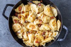 a skillet filled with dumplings and bacon on top of a gray countertop