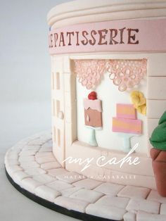 there is a cake that looks like a store front with a cupcake in the window