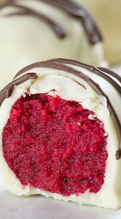 two chocolate covered desserts with white and red frosting