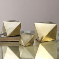 three gold colored objects sitting on top of a glass table