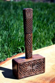 a wooden block with a carved design on it sitting in the middle of some grass