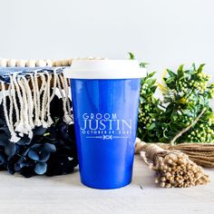 a blue coffee cup sitting on top of a table next to some plants and other decorations