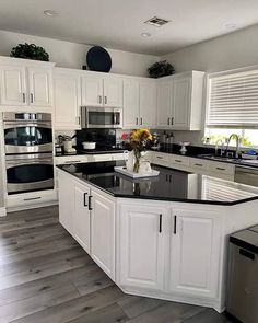 a large kitchen with white cabinets and black counter tops, stainless steel appliances and dishwasher