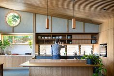 a man is standing in the middle of a kitchen with wooden cabinets and counter tops