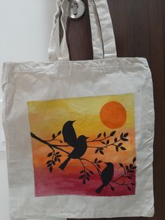 a white bag with a painting of two birds sitting on a tree branch at sunset