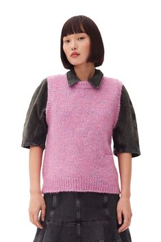 a woman wearing a pink sweater and black skirt