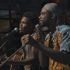 two men standing next to each other while holding microphones