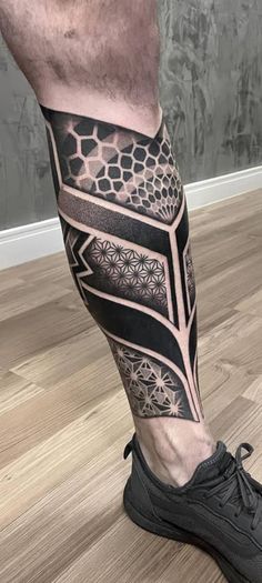 a man's leg with a black and white tattoo design on the lower part of his leg