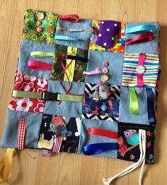 a piece of cloth covered in different types of ribbons and buttons on a wooden table