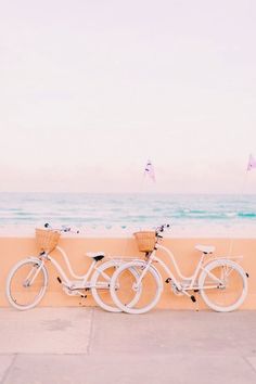 two bikes parked next to each other on the side of a road near the ocean