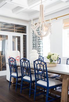 a dining room table with blue chairs and a chandelier