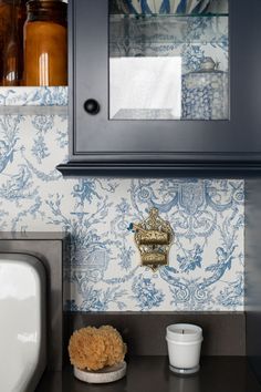 a blue and white wallpaper in a kitchen next to a sink with a mirror above it