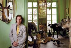 a man standing in front of a green wall with taxidermy on the walls