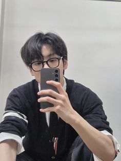 a young man taking a selfie in front of a mirror with his cell phone