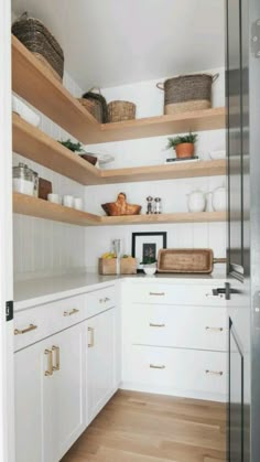 a kitchen with white cabinets and wooden shelves