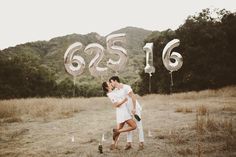 a man and woman are kissing in front of balloons with the numbers 665 on them