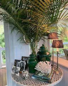 a table topped with green vases next to a palm tree and other decor items