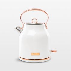 a white tea kettle with copper trimmings and a handle on the top, sitting in front of a white background