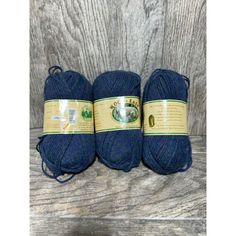 three skeins of blue yarn sitting on top of a wooden table