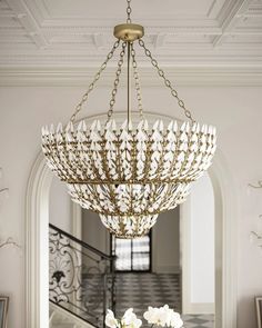 an elegant chandelier hangs from the ceiling above a table with flowers on it