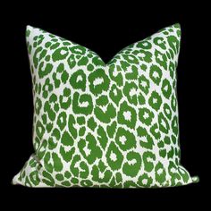 a green and white pillow with an animal print pattern on the front, sitting on a black background