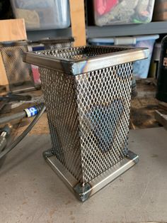 a metal trash can sitting on top of a table next to other boxes and tools