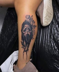 a woman's leg with a skull and flowers tattoo on her left calf area