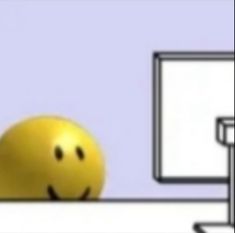 a smiley face sitting in front of a computer monitor