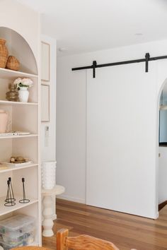 a room with white walls and shelves filled with vases, bookshelves and other items