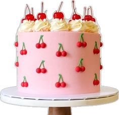 a pink cake with cherries and white frosting on a stand, topped with cherry slices