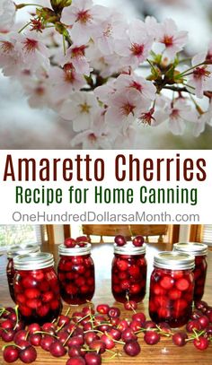 jars filled with cherries sitting on top of a wooden table next to cherry blossoms