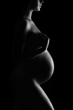 a pregnant woman poses for a black and white photo