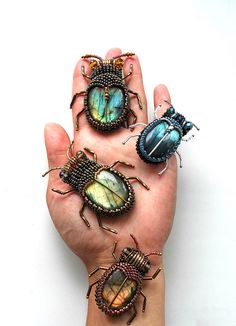 four bugs are sitting on the palm of someone's hand, and one beetle is laying down