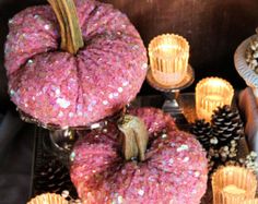 there are some pink pumpkins and candles on the table