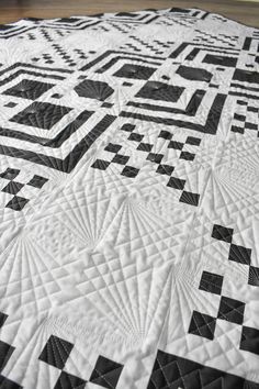 a black and white quilt on a wooden floor