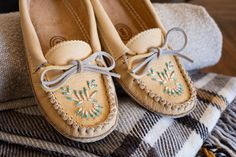 a pair of tan moccali shoes sitting on top of a pile of blankets