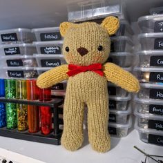 a teddy bear with a red bow sitting on top of a shelf in a craft room